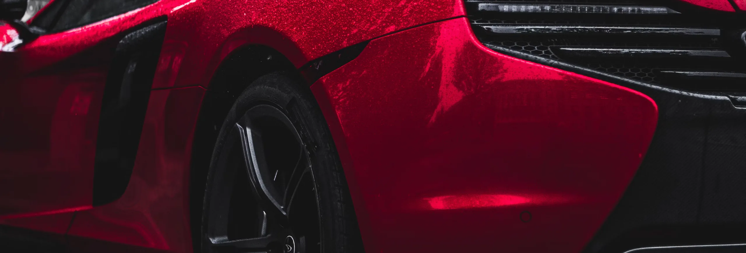 A red sports car beaded with rain