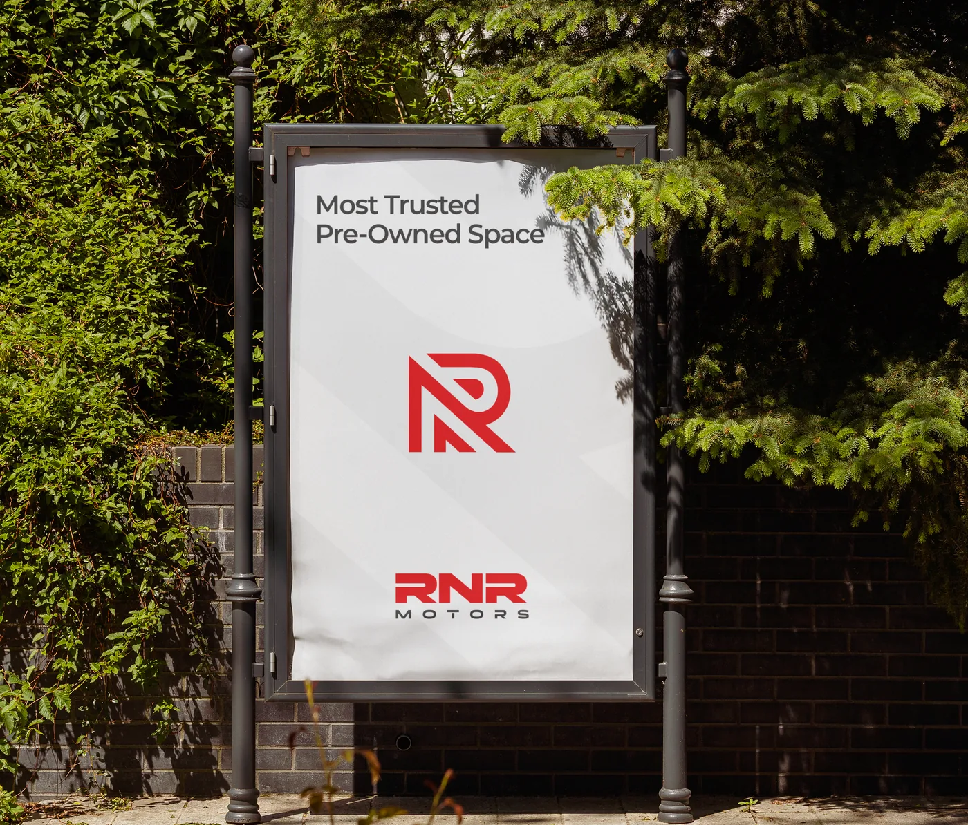 A street poster reading Most Trusted Pre-Owned Space, with the RNR monogram and wordmark