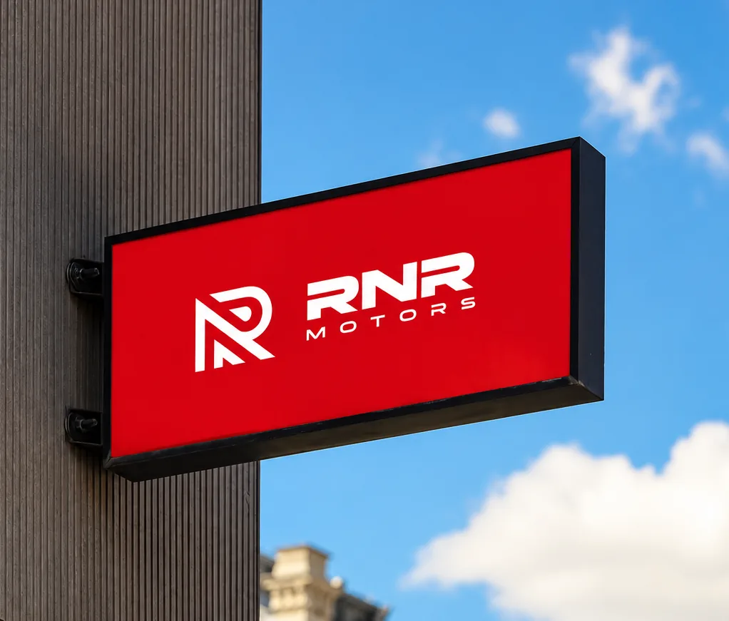 A red illuminated wall sign with the RNR Motors logo against a blue sky