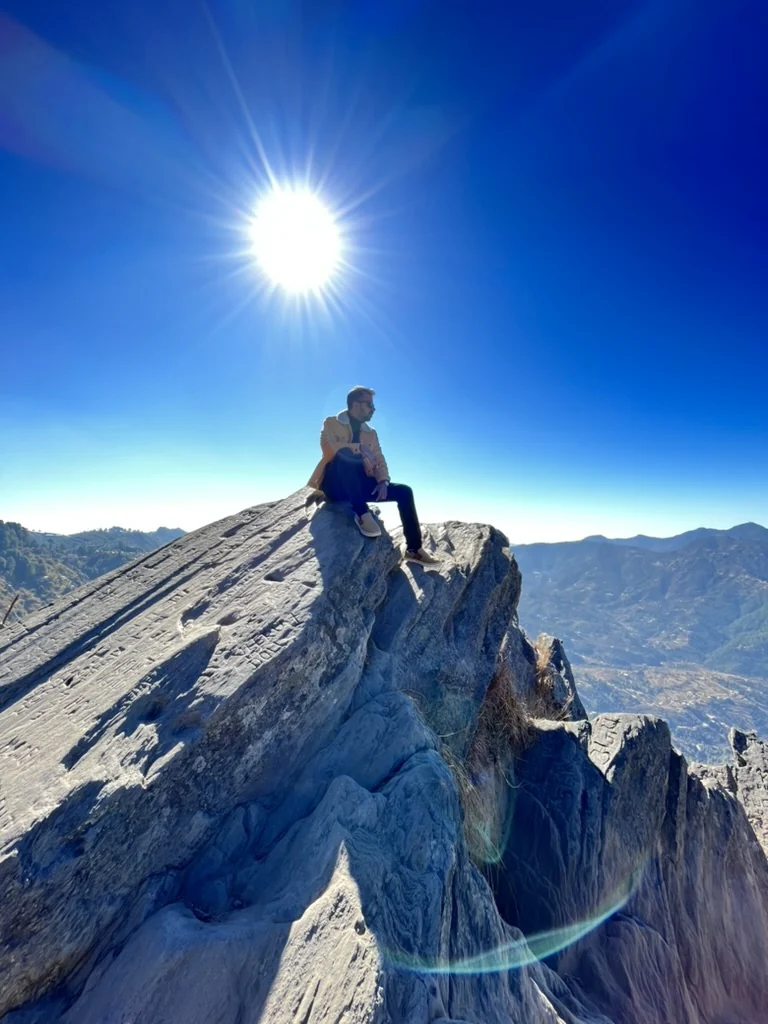 Sohan seated on a rocky summit beneath a bright sun